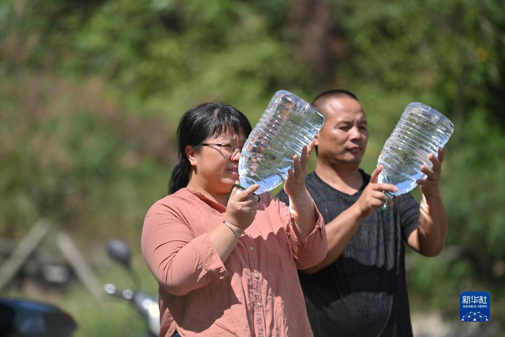 楊寧（左）在查看村民剛剛采集的水樣，為山泉水引水工程做準(zhǔn)備（10月8日攝）。新華社記者 黃孝邦 攝